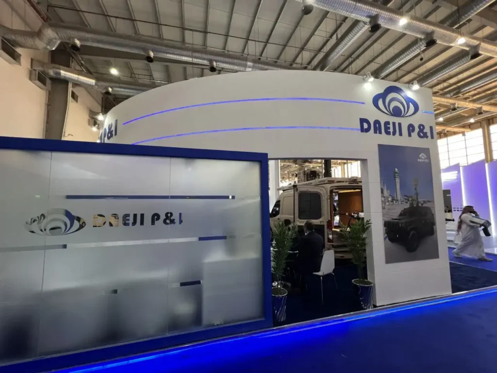 Front entrance of DAEJI P&I trade show booth showcasing defense vehicle display and branding