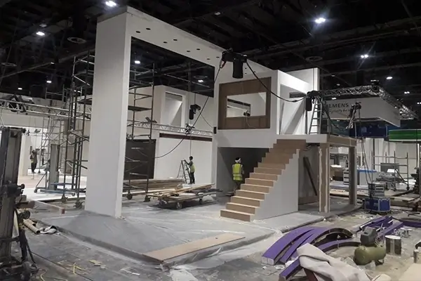 Large double-decker exhibition stand framework during construction before branding, lighting, and finishing installation