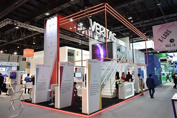 Completed VERITAS double-decker trade show booth with reception area, meeting spaces, and illuminated branding