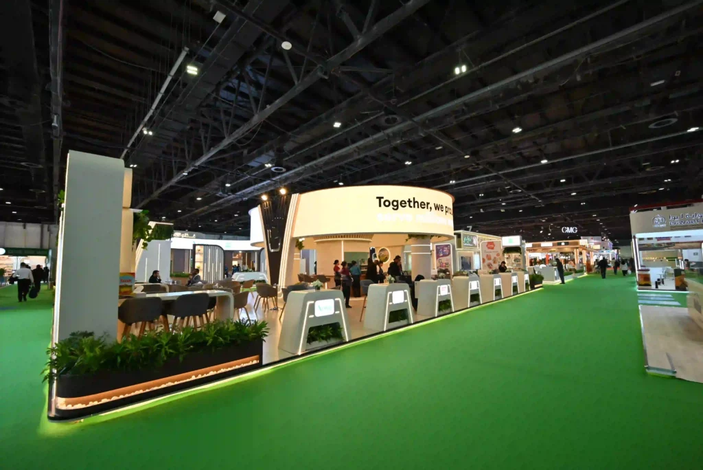 Custom exhibition stand with curved branding, seating areas, and illuminated display counters