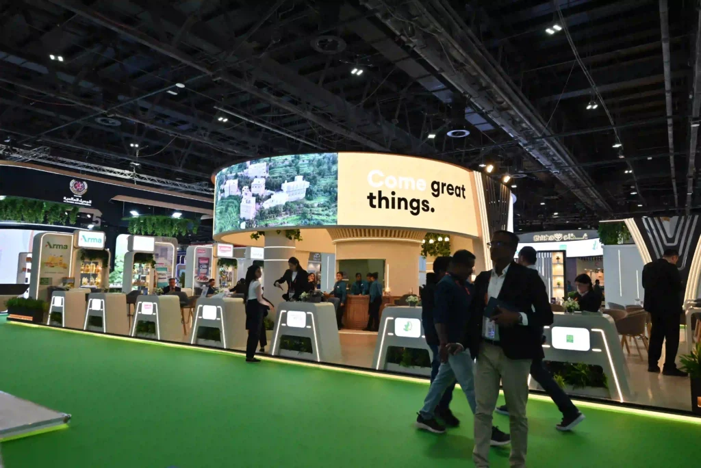 Custom exhibition stand with curved overhead branding and multiple visitor reception counters