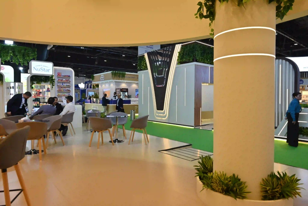 Trade show booth interior with seating, branded displays, and illuminated architectural features