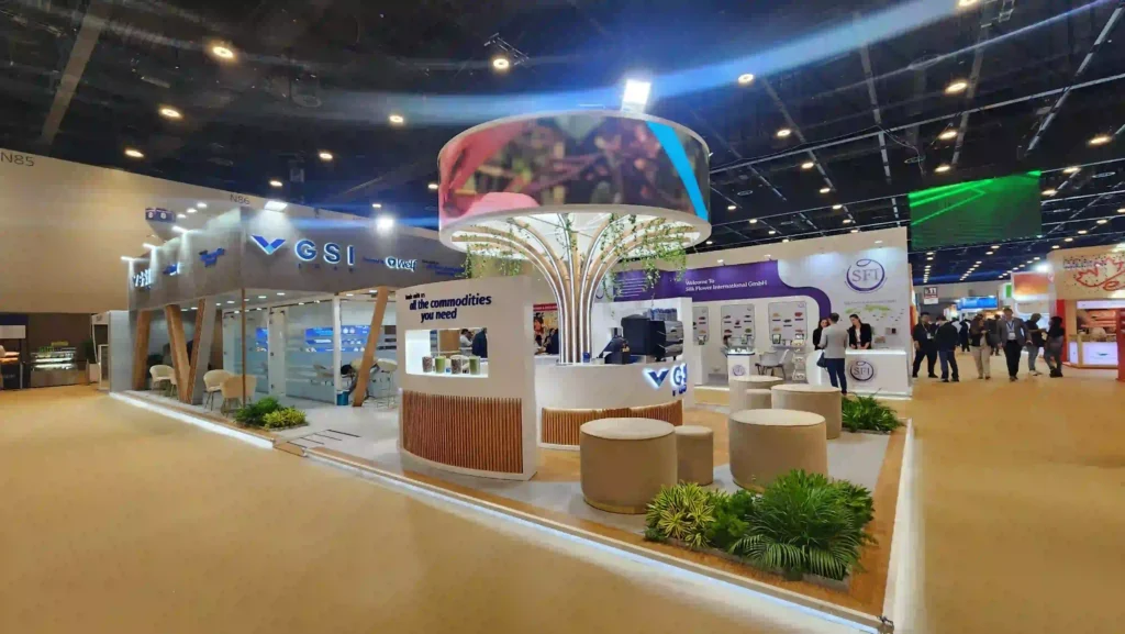 Branded trade show booth featuring curved counters, lounge seating, and overhead circular display
