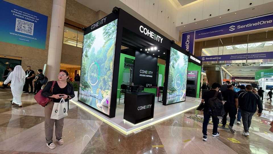 Cohesity trade show booth with immersive digital displays and branded reception at GITEX