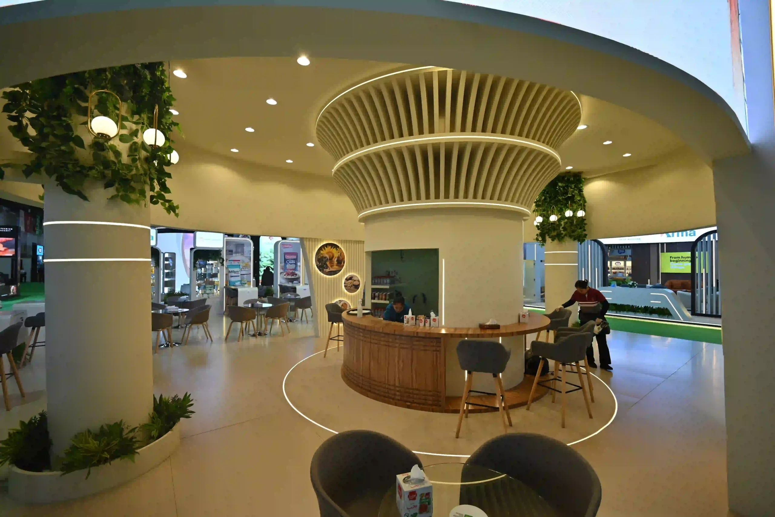 Exhibition booth interior featuring circular reception counter, seating, and decorative ceiling design