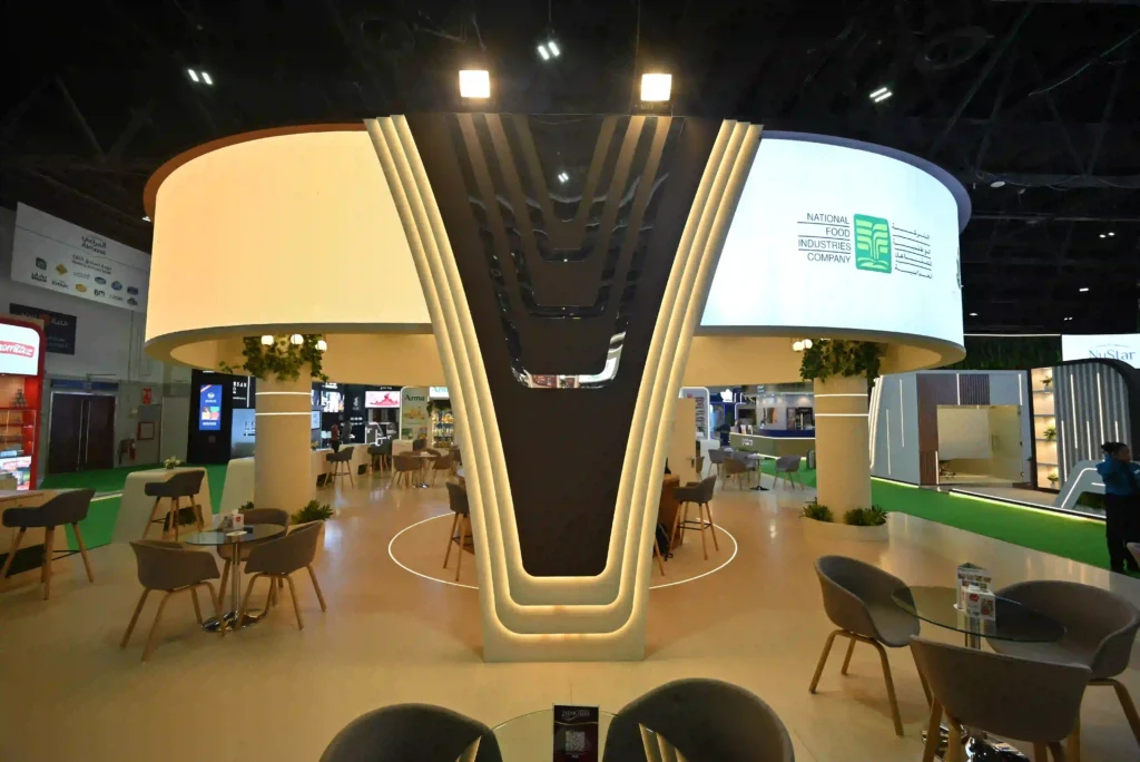 Custom exhibition stand with dramatic illuminated central column and open seating areas