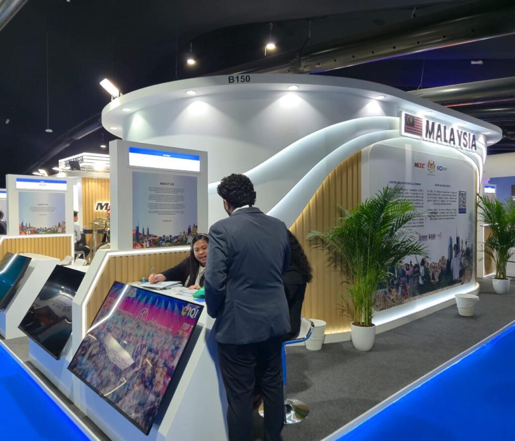 Malaysia Digital custom exhibition booth with interactive screens, curved architecture, and visitor reception