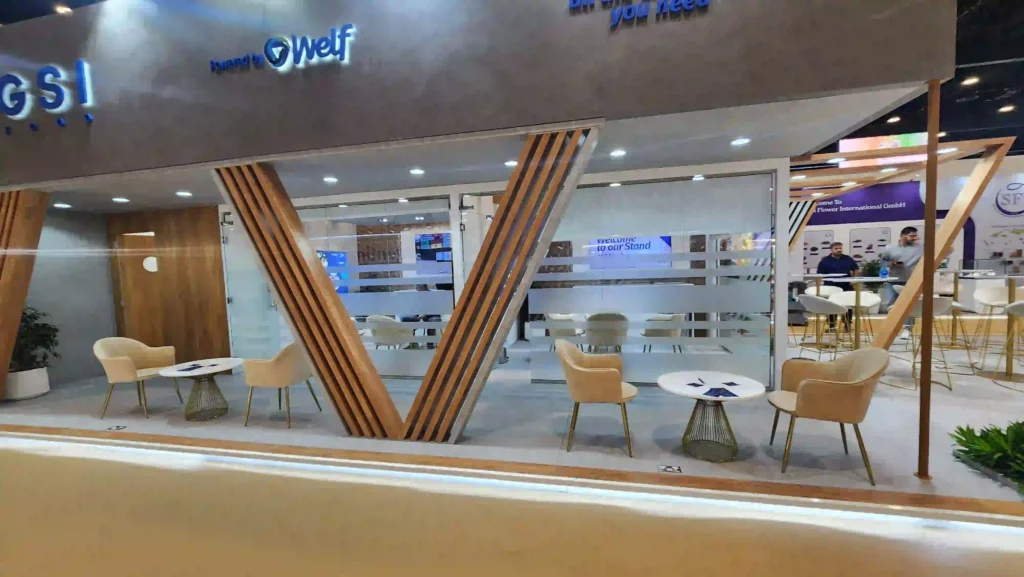 Modern exhibition booth interior featuring lounge seating, glass walls, and wooden structural panels