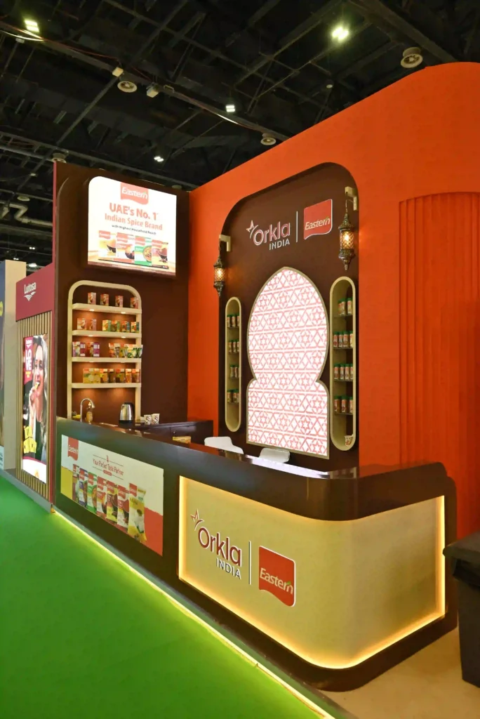Custom exhibition stand reception area featuring Orkla India branding and product displays