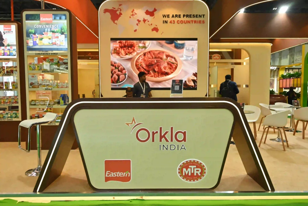 Orkla India exhibition booth featuring product displays, digital screen, and branded reception counter