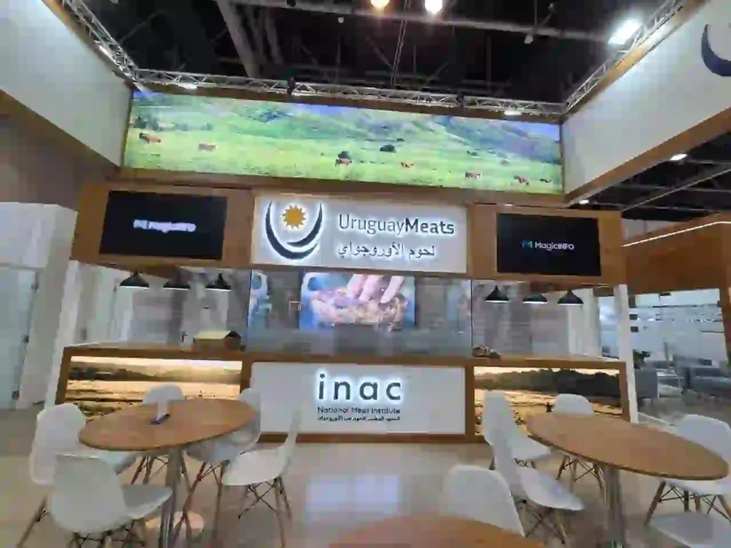 Uruguay Meats trade show booth interior with dining tables and digital displays