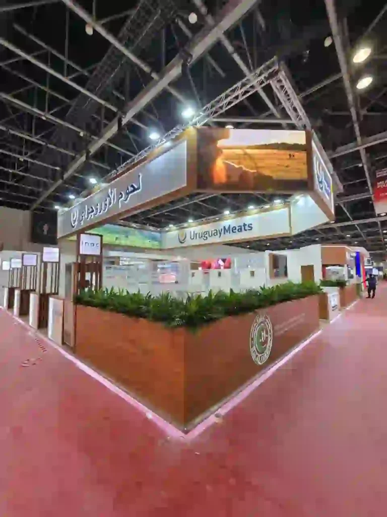 Uruguay Meats custom exhibition stand with illuminated branding, screens, and wooden finishes