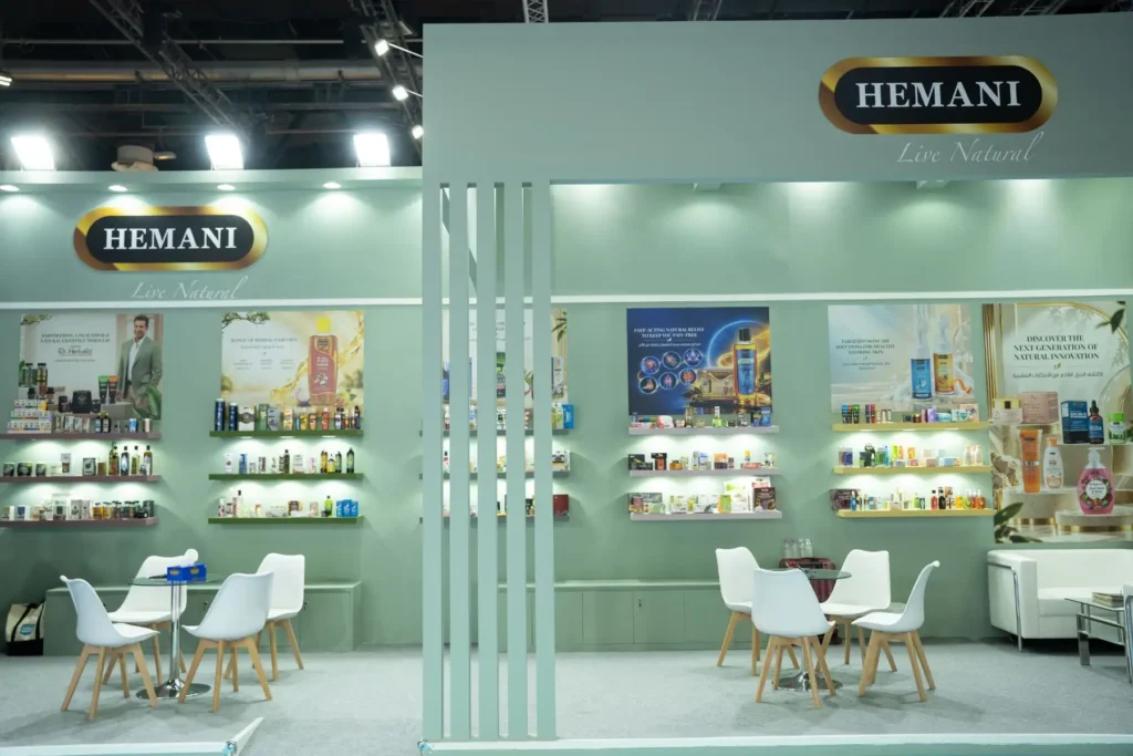 Hemani Herbal exhibition booth with product displays, reception counter, and trade show visitors