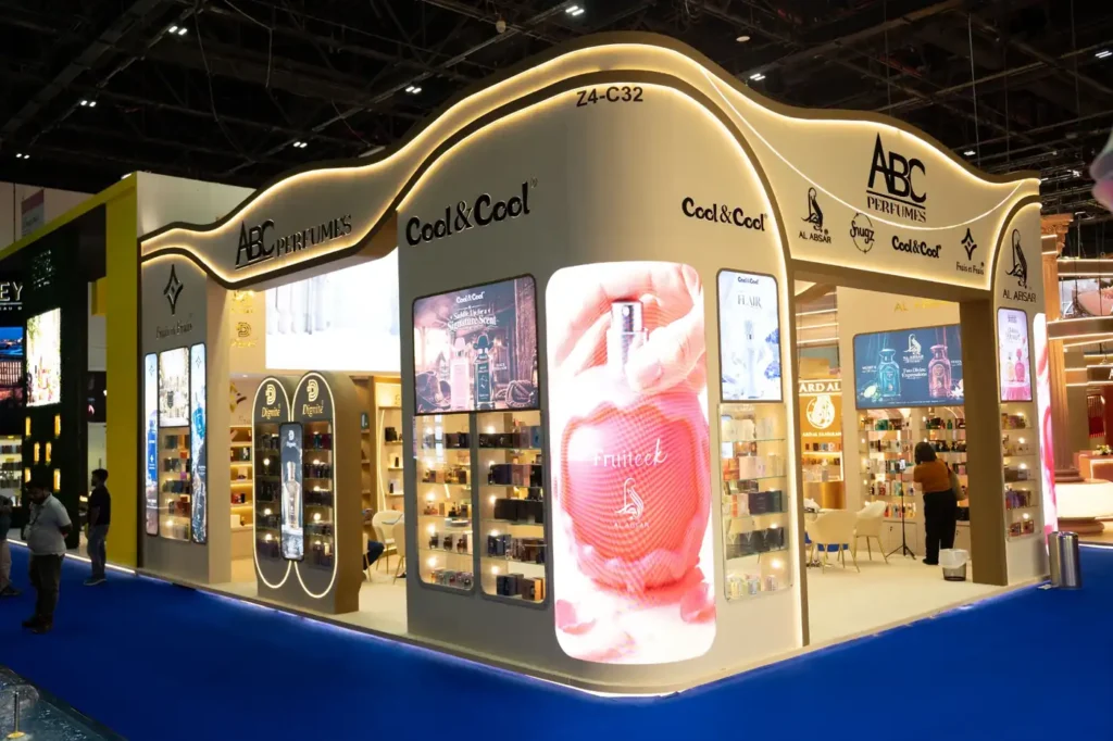 Luxury perfume trade show booth with digital advertising screens and illuminated display shelves.