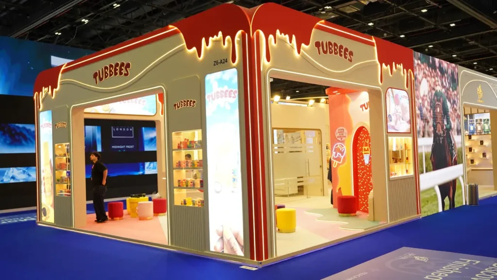 Modern Tubbees exhibition stand with bright LED accents, open entrances, and interactive product displays.
